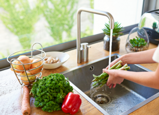 A woman washing vegetables in a kitchen sink.