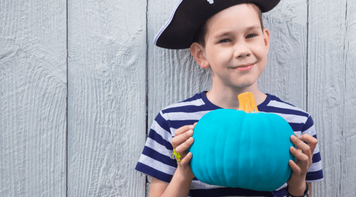 A boy holding a teal pumpkin.