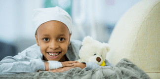 A child with cancer laying on a bed.