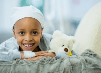 A child with cancer laying on a bed.
