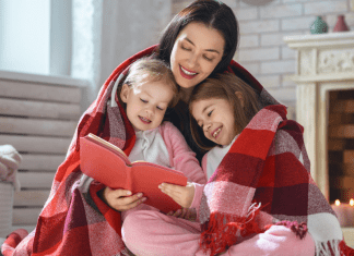 A mother reading a book to her daughters.