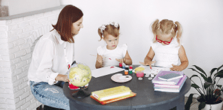 A woman doing arts and crafts with two children.