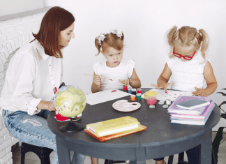 A woman doing arts and crafts with two children.
