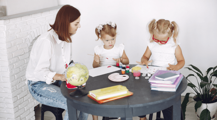 A woman doing arts and crafts with two children.