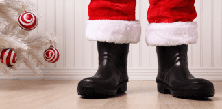 Santa's boots standing by a white Christmas tree.