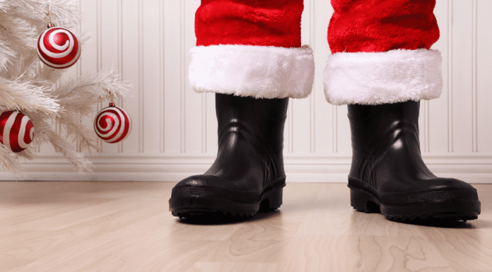 Santa's boots standing by a white Christmas tree.