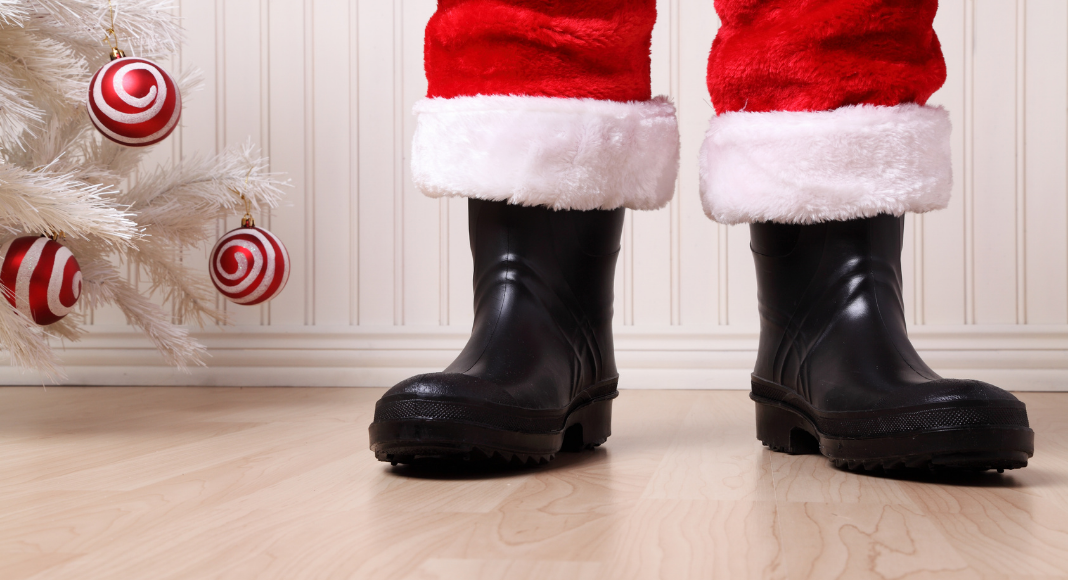 Santa's boots standing by a white Christmas tree.