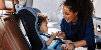 A mother buckling her son into his car seat.