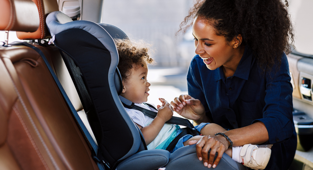 A mother buckling her son into his car seat.