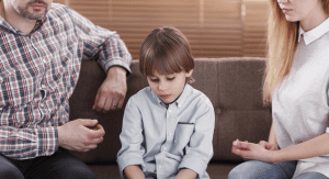 Sad child sitting in between his parents.