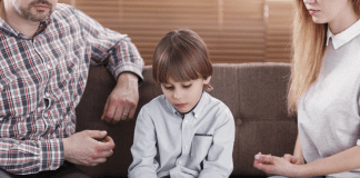 Divorce: How I Deal With Tough Questions From the Kids Sad child sitting in between his parents.