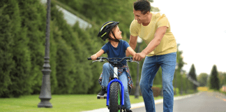 A dad teaching his son to ride a bike.