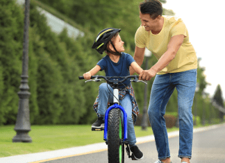 A dad teaching his son to ride a bike.