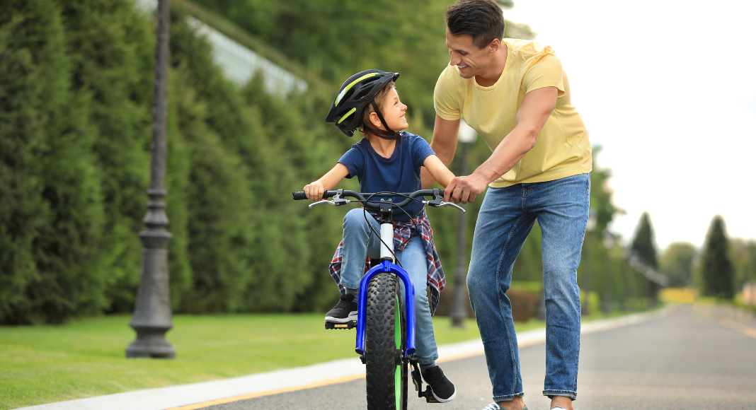 A dad teaching his son to ride a bike.