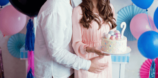 A man and woman holding a gender reveal cake.