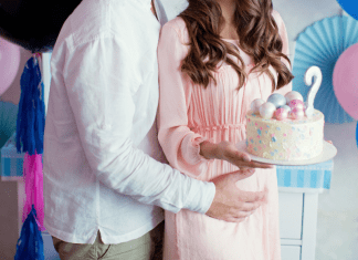 A man and woman holding a gender reveal cake.