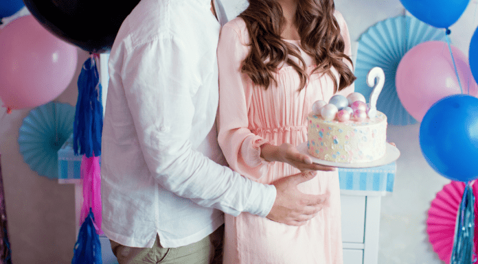 A man and woman holding a gender reveal cake.