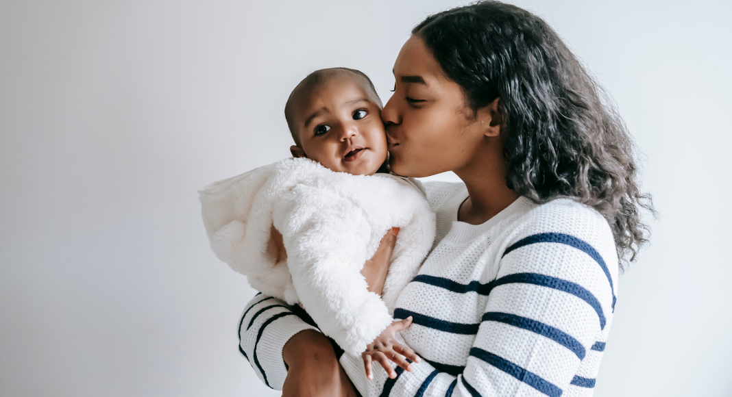 A mother kissing her baby.