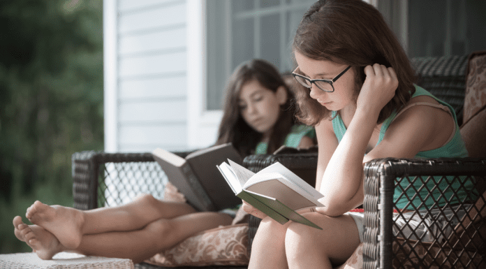 Girls doing their summer reading outside.