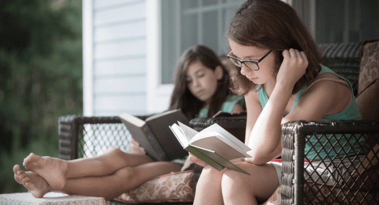 Girls doing their summer reading outside.