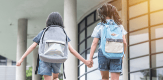 Two girls holding hands going back to school.