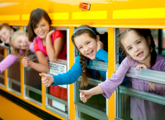 Kids sticking their heads out of a school bus.