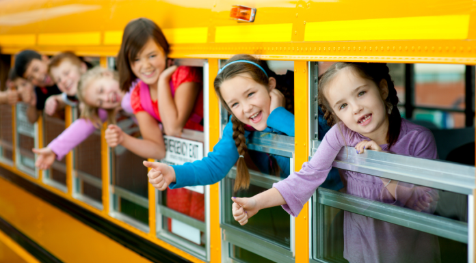 Kids sticking their heads out of a school bus.