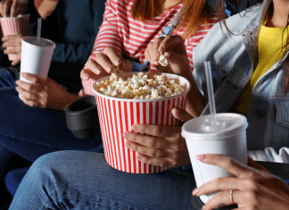 Women eating popcorn and drinking soda in a movie theatre.