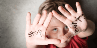 Supporting Children in the Battle Against Bullies A kid holding up he hands with the words "stop byllying."