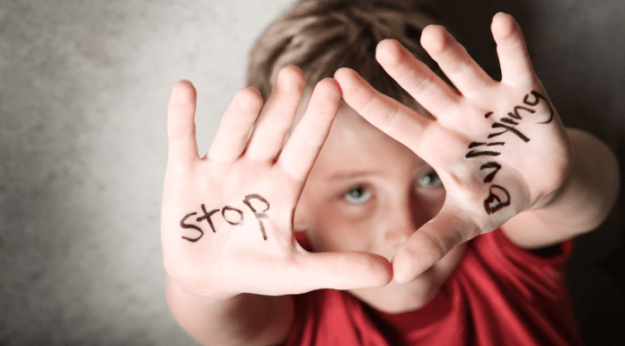 A kid holding up he hands with the words "stop byllying."