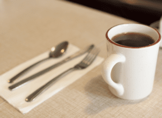 A cup of coffee and a table setting at a diner counter.