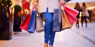 Raise Your Consciousness This Holiday Season and Not Just Consumption A woman walking holding shopping bags.