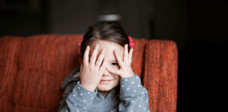 In Her Own Time A girl hiding behind her hands.