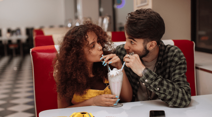 A couple sharing a milkshake on a date.