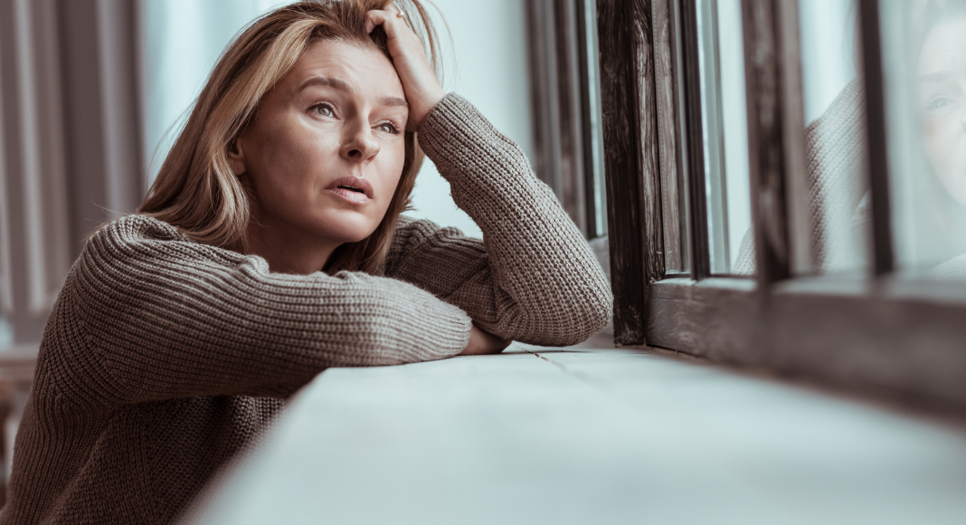 A woman upset looking out the window.
