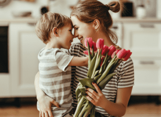 A boy hugging his mom and giving her flowers on Mother's Day.
