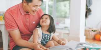 A dad reading a book to his daughter to teach kindness and empathy.