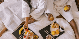 The Best Weekend Getaways in or Around Westchester County A couple eating breakfast in a hotel bed on a romantic getaway.