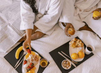 A couple eating breakfast in a hotel bed on a romantic getaway.