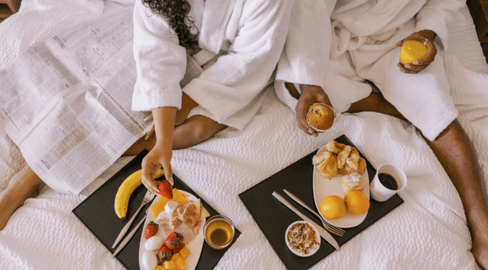 The Best Weekend Getaways in or Around Westchester County A couple eating breakfast in a hotel bed on a romantic getaway.