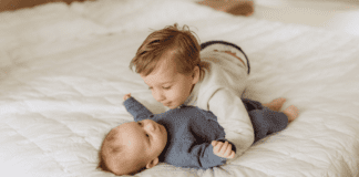 A toddler boy kissing his baby brother.