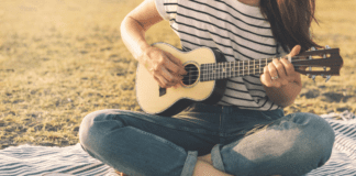 Summer and Music are the Perfect Pair A woman playing the guitar on the beach.