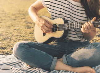 A woman playing the guitar on the beach.