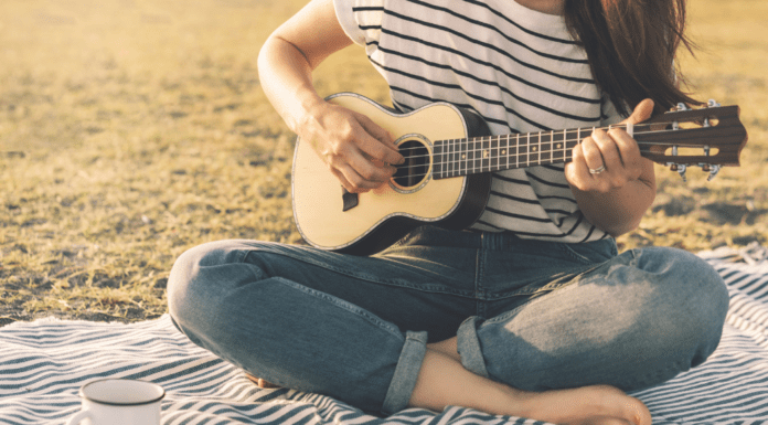 Summer and Music are the Perfect Pair A woman playing the guitar on the beach.