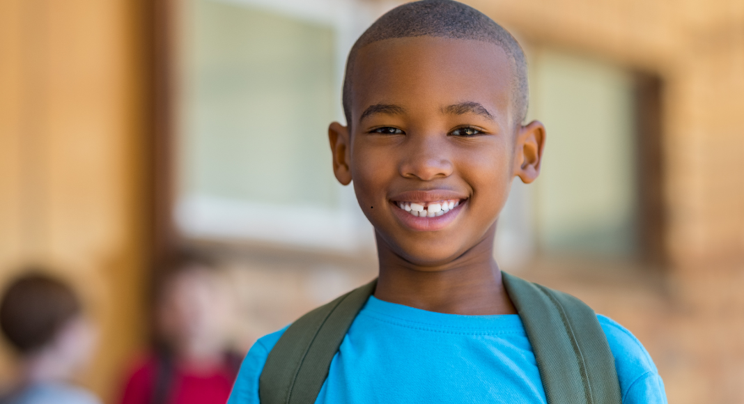 A black boy wearing a backpack.