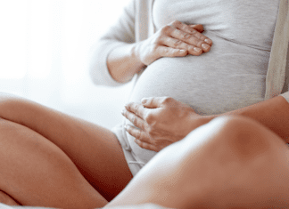 The C-Section Essentials – 7 Things You Need Post Surgery A pregnant woman holding her belly.