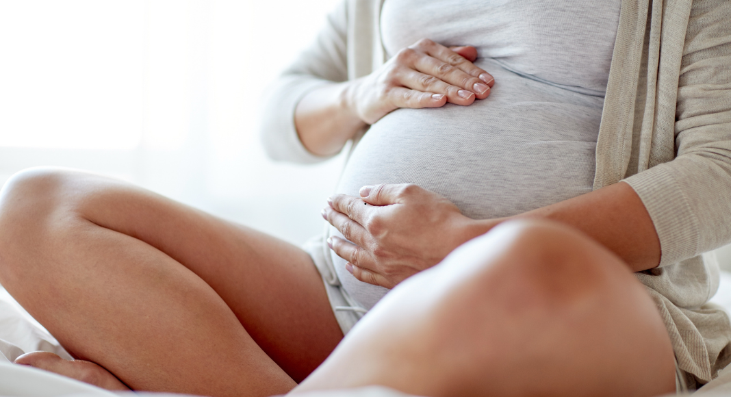 A pregnant woman holding her belly.