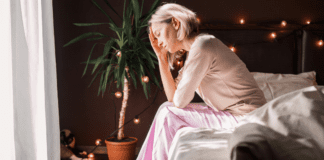 A woman sitting alone in her bedroom.