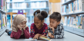 Parenting as Social Justice: A Culturally Responsive Columbus Day Three children laying on their bellies reading a book.