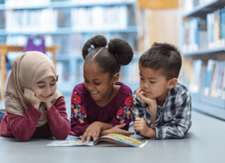 Parenting as Social Justice: A Culturally Responsive Columbus Day Three children laying on their bellies reading a book.